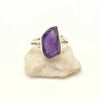 Silver ring with a raw purple amethyst gemstone on a white background