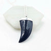 Black onyx animal tooth-shaped pendant on a white background
