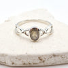 Silver ring with an oval labradorite stone on a marble surface