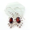 Silver earrings with red garnet gemstones on a white background