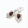 Silver earrings with red garnet gemstones on a white background