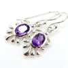 Silver earrings with purple amethyst gemstones on a white background