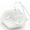 Silver tree-of-life earrings on a white stone with a white background