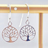 Tree-of-life-shaped earrings on a gold stand against a white background