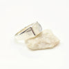 Silver ring with a moonstone on a white stone against a white background