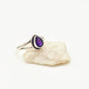Silver ring with a purple amethyst gemstone on a white stone