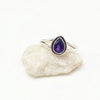 Silver ring with a purple amethyst gemstone on a white stone surface