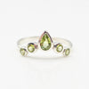 Silver ring with green gemstones on a white background