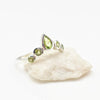 Silver ring with green gemstones on a white stone