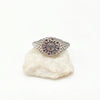 Silver signet ring with a sun with face engraved on a white stone on white background