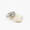 Silver signet ring with a sun with face engraved on a white stone on white background
