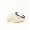 Silver ring with floral design on a white rock on a white background