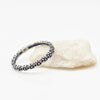 Silver ring with floral design on a white rock on a white background