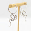 Silver snake hoop earrings on a gold stand against a white background