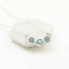 Silver necklace with three cloudy aquamarine gemstones on a white background