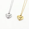 Two heart-shaped pendant necklaces on delicate chains, one in polished silver and one in polished yellow gold, Part of our engravable collection. Made in stainless steel