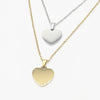 Two heart-shaped pendant necklaces on delicate chains, one in polished yellow gold and one in polished silver, made with stainless steel. Part of ourengravable range