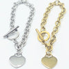Two heart-shaped toggle chain bracelets displayed side by side on a white background, one in polished silver and the other in polished yellow gold. made with stainless steel