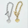 Two heart charm chain bracelets, one in silver and one in yellow gold, displayed side-by-side on a plain white background.