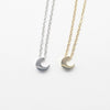 A minimalist high-polish stainless steel necklace featuring a dainty, solid crescent moon pendant on a delicate cable chain, Availble in Silver and Gold. Part of the Engravable Collection