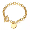 A gold chain bracelet with a toggle clasp and a small flat heart-shaped charm, shown on a plain white background.