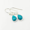 A pair of silver drop earrings with teardrop-shaped turquoise 